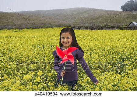 Picture - Portrait of a girl holding a toy windmill in a field . Fotosearch