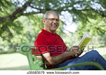 Portrait of a senior man reading a book in a park View Large Photo Image Stock Photo - Portrait of a senior man reading a book in a park. Fotosearch