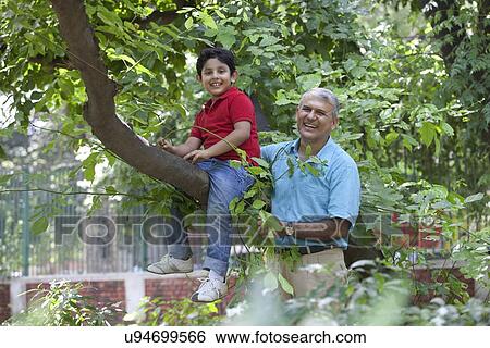 Stock Photograph - Portrait of boy sitting on a tree branch. Fotosearch