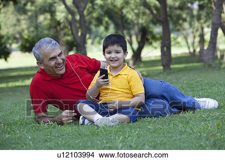 Portrait of boy sitting with his grandfather listening to music View Large Photo Image Picture - Portrait of boy sitting with his grandfather listening to music. Fotosearch