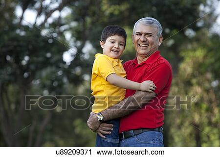Stock Image - Portrait of grandfather and grandson in a park. Fotosearch