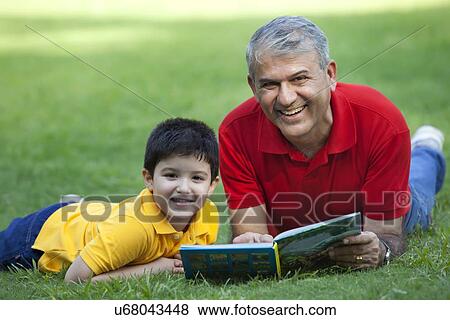 Stock Photo - Portrait of grandfather and grandson with a book in a park. Fotosearch