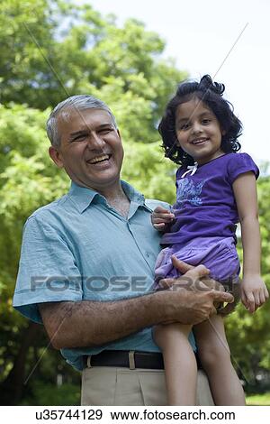 Stock Photo - Portrait of grandfather holding granddaughter. Fotosearch