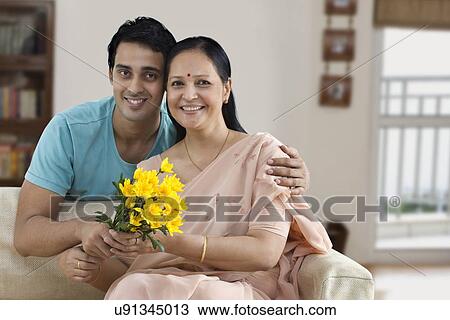 Stock Image - Portrait of smiling mother and young son holding flowers . Fotosearch