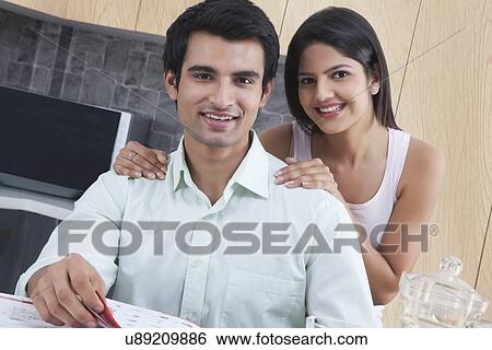 Portrait of smiling young couple in kitchen View Large Photo Image Stock Photograph - Portrait of smiling young couple in kitchen. Fotosearch