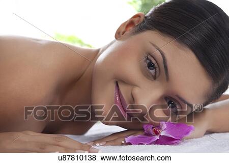 Stock Photo - Portrait of smiling young woman lying on table at spa . Fotosearch