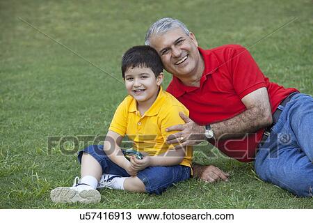 Stock Image - Portrait of young boy with grandfather in a park. Fotosearch