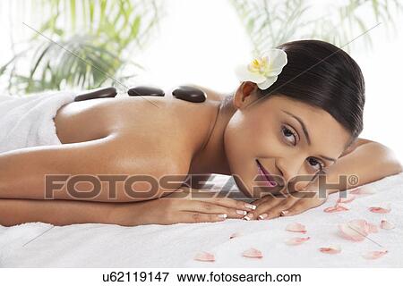 Stock Photo - Portrait of young woman getting hot stone treatment . Fotosearch