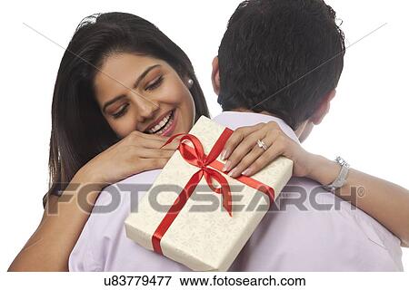 Stock Photo - Rear view of a woman holding a gift smiling. Fotosearch