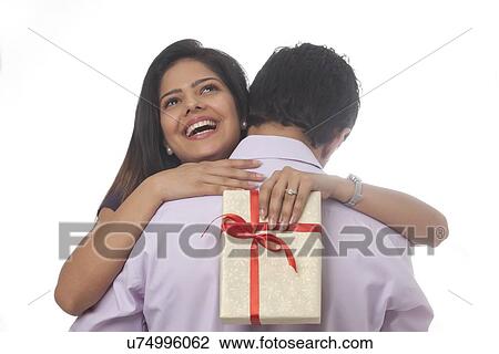 Stock Image - Rear view of a woman with a gift hugging. Fotosearch