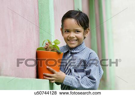Stock Photo - School girl holding a potted plant . Fotosearch