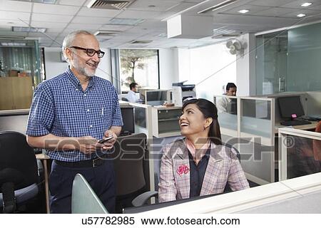 Stock Photography - Senior man and woman having a chat in office. Fotosearch