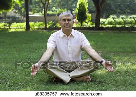 Stock Photo - Senior man meditating in park. Fotosearch