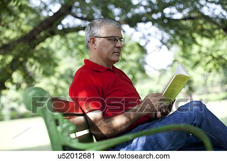 Senior man reading a book in a park View Large Photo Image Stock Image - Senior man reading a book in a park. Fotosearch