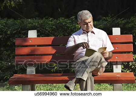 Senior man reading a book in a park View Large Photo Image Stock Image - Senior man reading a book in a park. Fotosearch