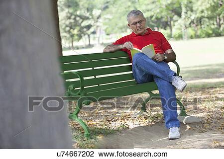 Senior man reading a book in a park View Large Photo Image Stock Image - Senior man reading a book in a park. Fotosearch