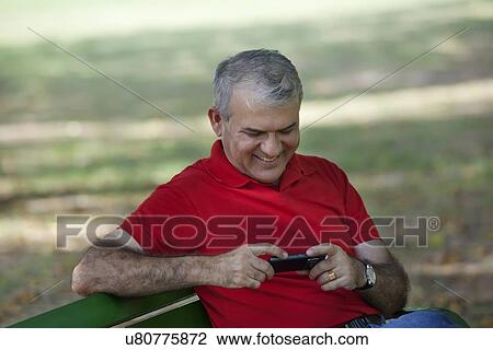 Stock Image - Senior man reading an sms on a mobile phone. Fotosearch