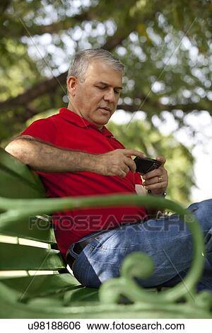 Senior man reading an sms on a mobile phone View Large Photo Image Stock Photograph - Senior man reading an sms on a mobile phone. Fotosearch