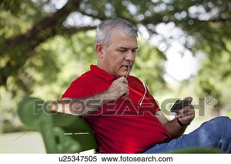 Senior man reading an sms on a mobile phone View Large Photo Image Stock Photography - Senior man reading an sms on a mobile phone. Fotosearch