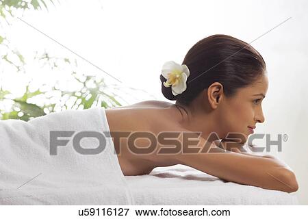 Stock Photo - Side view of smiling woman lying on massage table . Fotosearch