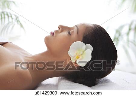 Stock Photo - Side view of young woman lying on massage table . Fotosearch