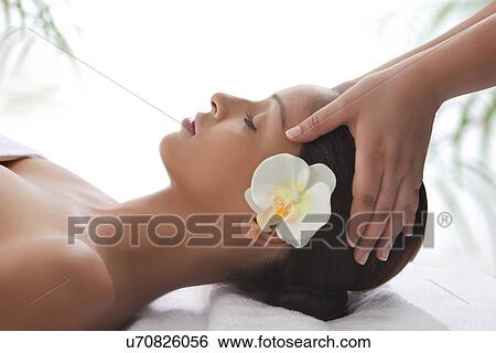 Side view of young woman on massage table getting head massage View Large Photo Image Stock Photograph - Side view of young woman on massage table getting head massage . Fotosearch