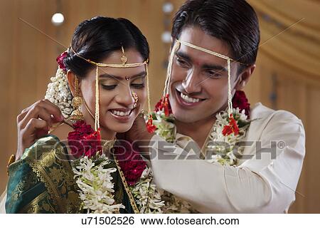 Smiling groom performing rituals with his bride View Large Photo Image Stock Photograph - Smiling groom performing rituals with his bride . Fotosearch