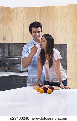 Smiling man feeding fresh apple to woman in kitchen View Large Photo Image Stock Image - Smiling man feeding fresh apple to woman in kitchen. Fotosearch
