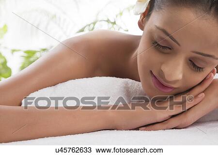 Stock Image - Smiling woman on massage table at spa . Fotosearch