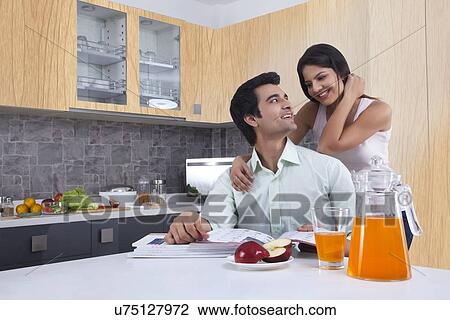 Smiling young couple looking at each other in kitchen View Large Photo Image Stock Image - Smiling young couple looking at each other in kitchen. Fotosearch
