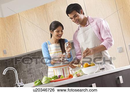 Smiling young couple preparing fresh salad in kitchen View Large Photo Image Stock Photograph - Smiling young couple preparing fresh salad in kitchen. Fotosearch