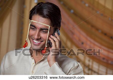Stock Photograph - Smiling young groom talking on phone call . Fotosearch