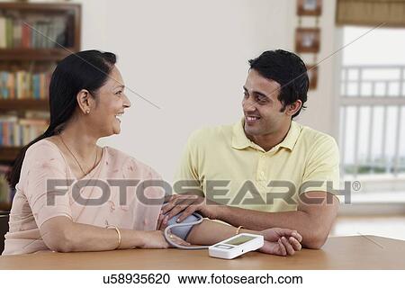 Smiling young man checking blood pressure of his mother View Large Photo Image Stock Image - Smiling young man checking blood pressure of his mother . Fotosearch