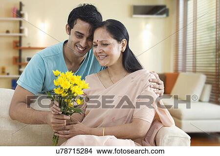 Picture - Smiling young man giving flowers to his mother . Fotosearch