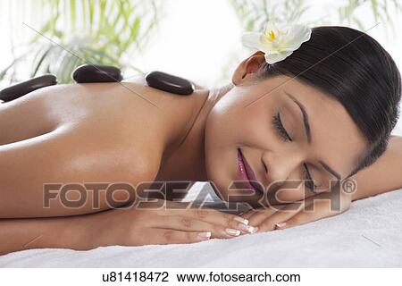 Smiling young woman getting hot stone treatment View Large Photo Image Stock Image - Smiling young woman getting hot stone treatment . Fotosearch
