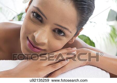 Stock Photo - Smiling young woman on massage table at spa . Fotosearch