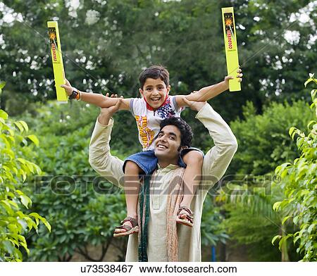 Son sitting on his fathers shoulders View Large Photo Image Stock Photo - Son sitting on his fathers shoulders . Fotosearch