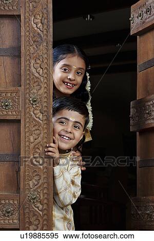 Stock Photography - South Indian boy and girl peeping from the doorway . Fotosearch