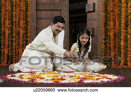 Stock Image - South Indian man and daughter making a rangoli . Fotosearch