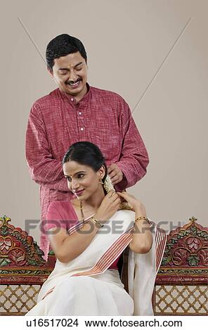 South Indian man tying a Gajra on his wife's hair View Large Photo Image Picture - South Indian man tying a Gajra on his wife's hair . Fotosearch