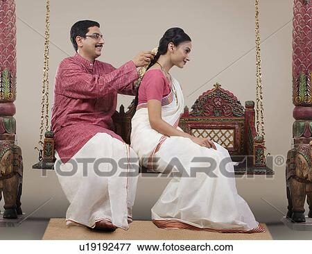 Stock Photo - South Indian man tying a Gajra on his wife's hair . Fotosearch