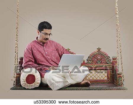 South Indian man working on a laptop View Large Photo Image Stock Image - South Indian man working on a laptop . Fotosearch