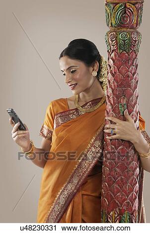 Stock Image - South Indian woman looking at her mobile phone . Fotosearch