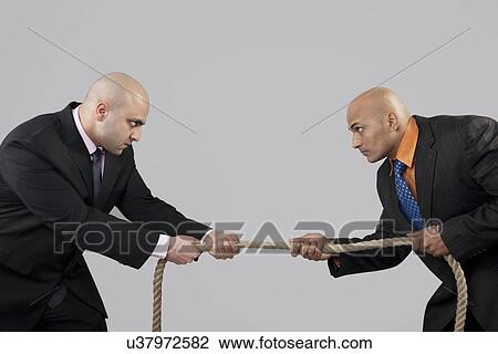 Stock Image - Tug of war between two businessmen . Fotosearch