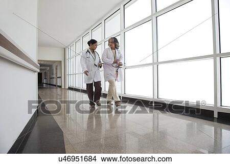 Two doctors in discussion walking down corridor View Large Photo Image Picture - Two doctors in discussion walking down corridor. Fotosearch