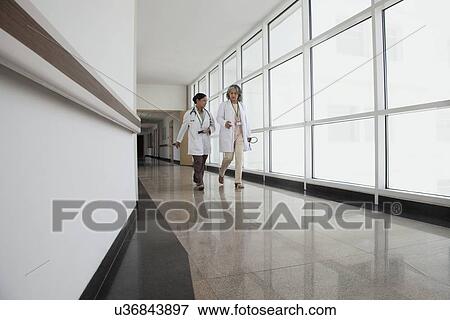 Stock Photo - Two doctors in discussion walking down corridor. Fotosearch