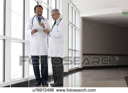 Two doctors looking at a report on a digital tablet View Large Photo Image Stock Photo - Two doctors looking at a report on a digital tablet. Fotosearch