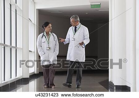 Stock Image - Two doctors talking in corridor of hospital. Fotosearch