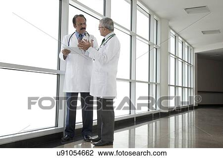 Two doctors talking in corridor of hospital View Large Photo Image Stock Image - Two doctors talking in corridor of hospital. Fotosearch