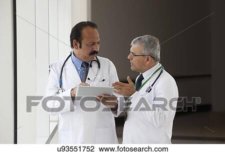 Two doctors talking in corridor of hospital View Large Photo Image Stock Image - Two doctors talking in corridor of hospital. Fotosearch